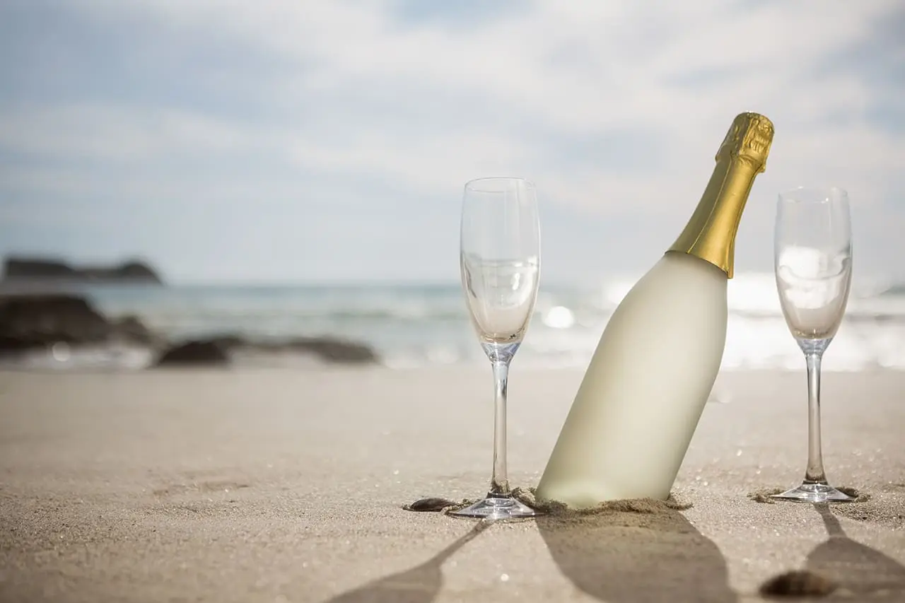 Bouteille de champagne à la plage avec 2 flûtes